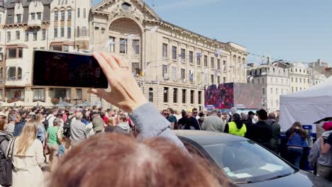 Riga,-Latvia,-Dome-Square,-a-woman-films-on-her-phone-how-people-watch-a-hockey-game-from-outdoor-screens