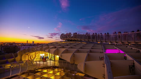 People-enjoys-Setas-de-Sevilla-after-sunset,-time-lapse-view