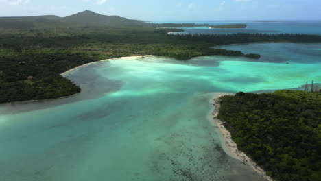 Aerial-parallax-over-beautiful-lagoon,-white-sand-beach,-and-N'ga-peak-in-the-background,-Isle-of-Pines