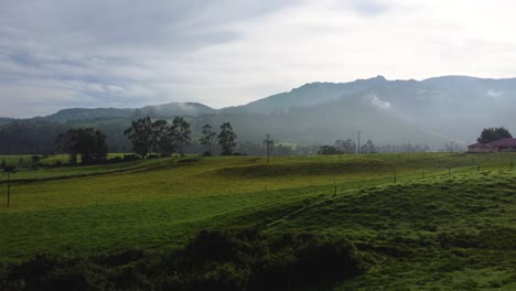 Leichter-Nebel-Auf-Einer-Großen-Grasfläche-Mit-Hügeln-Im-Hintergrund