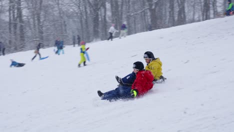 Niños-Divirtiéndose-Deslizándose-Sobre-La-Nieve-En-Invierno-Con-Nevadas-En-Bruselas,-Bélgica