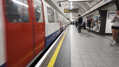 Bakerloo-Line-Zug-Kommt-Am-Bahnsteig-Der-Oxford-Street-An,-Pendler-Warten-Hinter-Der-Gelben-Linie