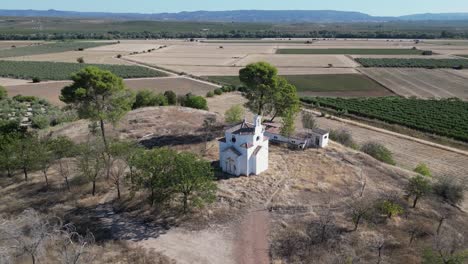 Aerial-view-of-architectural-elegance-at-La-Ermita-del-Poblado-de-San-Julián,-a-timeless-emblem-of-spiritual-dedication-in-Marmolejo,-framed-by-the-scenic-backdrop-of-agricultural-fields