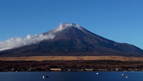 Majestic-Mount-Fuji-with-snow-cap,-clear-sky,-and-nearby-lake