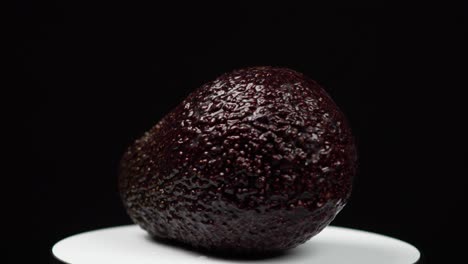 Nahaufnahme-Einer-Ganzen-Leuchtenden-Avocado,-Die-Auf-Schwarzem-Hintergrund-Rotiert