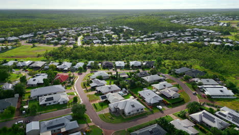 Aerial-drone-of-tropical-suburb-neighborhood-surrounded-by-lush-forest-on-sunny-day