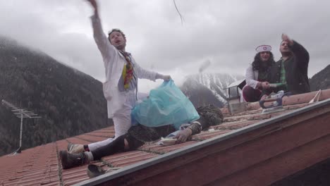 Scene-of-three-men-in-costumes-on-a-roof-during-the-Stilzer-Pfluagziachn-parade-in-Stlfs---Stelvio,-South-Tyrol,-Italy