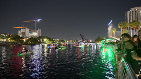 Young-couples-and-families-watch-festive-Christmas-boat-parade-with-beautifully-decorated-vessels