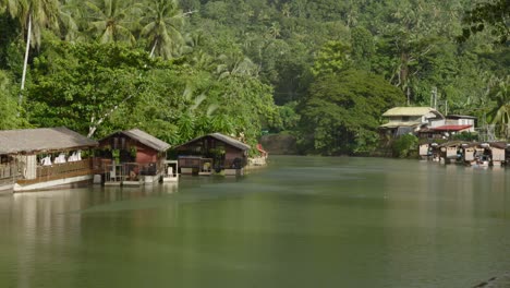 Cabañas-Junto-Al-Río-Enclavadas-En-Una-Exuberante-Vegetación-A-Lo-Largo-Del-Tranquilo-Río-Loboc-En-Filipinas