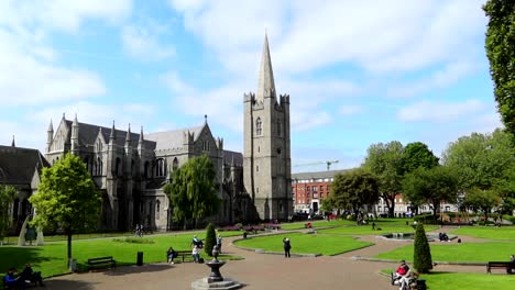 Static-wide-shot-of-St-Patrick-Cathedral-with-people-and-lush-lawn-on-sunny-day,-Dublin