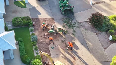 Yarrawonga,-Victoria,-Australia---6-March-2024:-Tree-workers-raking-up-rubbish-and-stump-grinder-operator-running-the-machine-in-a-suburban-street