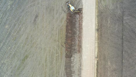 High-altitude-aerial-view-of-tractor-excavator-dig-and-repair-drainage-near-road