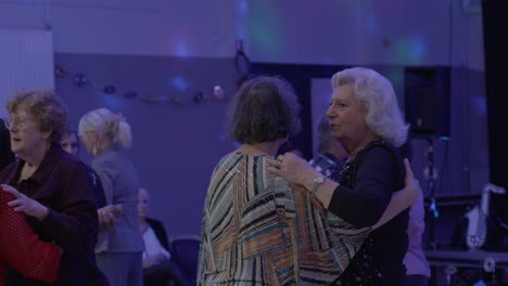 Hand-held-shot-of-senior-men-and-women-dancing-together-with-disco-lights