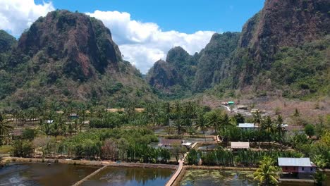 Aerial-of-beautiful-hidden-gem-Rammang-Rammang-Village-with-giant-limestone-cliffs-and-huge-karst-mountains-in-Sulawesi,-Indonesia