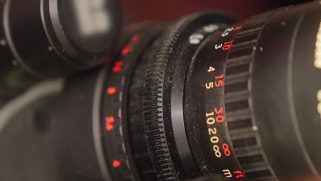Close-up-of-the-focus-and-zoom-rings-of-a-16mm-film-camera-lens,-which-are-turned-by-the-cameraman's-hand