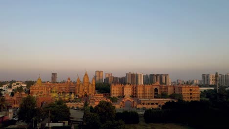 AERIAL-DRONE-VIEW-A-huge-grand-temple-is-seen-where-many-people-are-seen-outside-there-are-many-four-wheelers-and-also-parked-four-wheelers