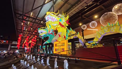 Colorful-Chinese-Dragons-Overlook-the-Entrance-of-The-Street-in-Ratchada,-Bangkok-with-a-Panning-Shot