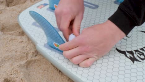 Close-up-Shot-of-Fins-Being-Installed-onto-Surfboard