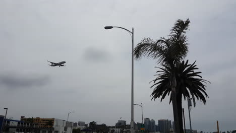 Flugzeug-Landet-Auf-Dem-Internationalen-Flughafen-Von-San-Diego,-Fliegt-über-Gebäuden-Und-Straßen-Unter-Bewölktem-Himmel,-Niedriger-Blickwinkel