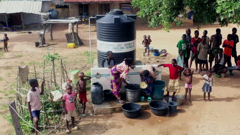 Dorfbewohner-In-Pila,-Nigeria-Rationieren-Wasser,-Das-Durch-Bohrloch--Und-Tanksystem-Geliefert-Wird