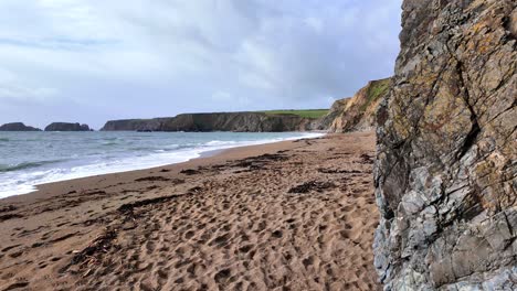 Bajando-Las-Mareas-Y-La-Playa-De-Arena-Con-Huellas-En-Las-Arenas-Doradas-De-Waterford,-Irlanda