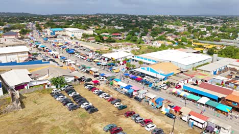 Spectators-park-cars-to-line-up-along-vibrant-booths-before-Karnaval-Grand-March,-aerial-Curacao