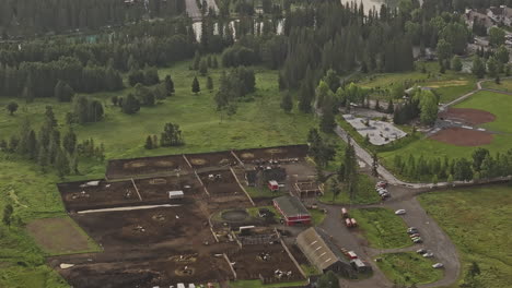 Banff-AB-Canada-Aerial-v15-zoomed-birds-eye-view-flyover-horse-stables-capturing-sunrise-glow-over-the-Bow-River-and-town-center-surrounded-by-forested-valley---Shot-with-Mavic-3-Pro-Cine---July-2023