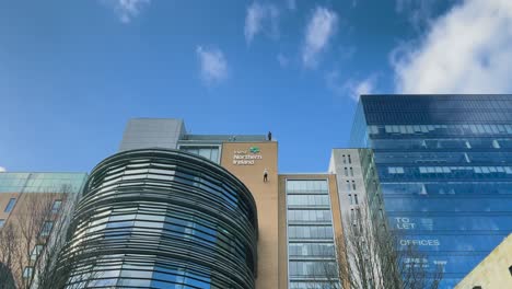 A-group-of-people-on-top-of-a-building-watching-a-man-abseiling-down-the-face-of-the-building-in-Belfast