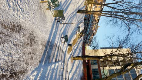 Woman-walks-up-stairs-in-snowy-park-in-sunlight-in-Stockholm,-vertical