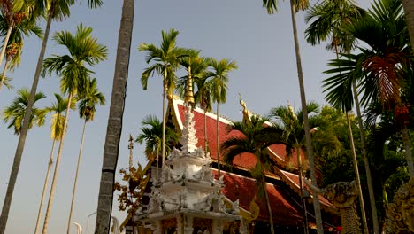 Atemberaubende-Filmische-Aussicht-Auf-Thailändischen-Tempel-Zwischen-Hohen-Palmen-Bei-Sonnenuntergang