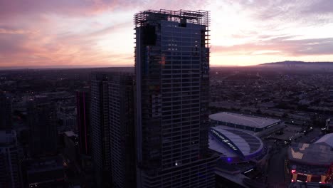 Wide-aerial-panning-shot-of-the-abandoned-Oceanwide-Plaza-graffiti-skyscrapers-at-sunset-in-downtown-Los-Angeles,-California