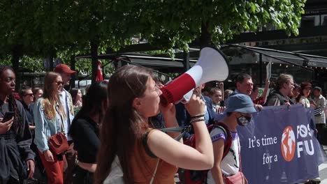 Woman-with-megaphone-and-protesters-with-signs-at-climate-march,-slomo