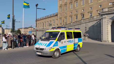 Police-vans-drive-by-Royal-Palace-on-national-day-in-Stockholm,-Sweden