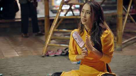 Pretty-Vietnamese-woman-in-traditional-yellow-dress-playing-Bai-Choi-game-and-clapping-hands-in-Hoi-An