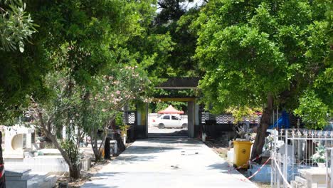 View-of-tree-lined-pathway-and-front-gates-with-passing-traffic-in-historic-site-of-Santa-Cruz-cemetery-in-capital-city-of-East-Timor,-Southeast-Asia