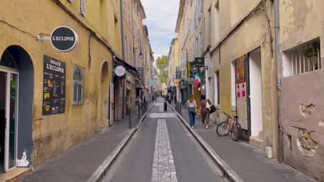 Scooter-and-people-by-restaurants-on-narrow-street-in-Aix-en-Provence