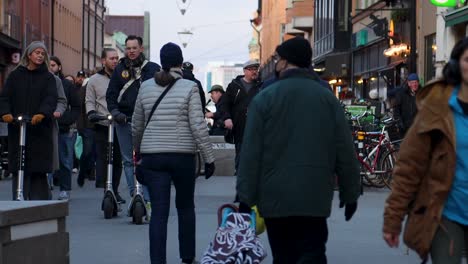 Young-people-ride-motorized-scooters-on-shopping-street-in-Stockholm