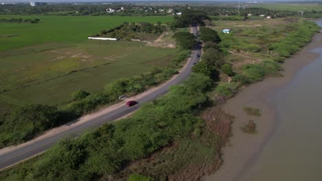 Toma-Aérea-De-Un-Dron-Siguiendo-Un-Automóvil-Rojo-En-La-Autopista-Chennai