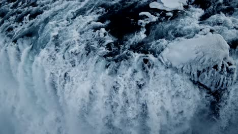 4K-drone-presents-cinematic,-dramatic,-and-distinctive-views,-featuring-an-extreme-close-up-of-the-Kirkjufell-waterfall-as-its-cascading-water-droplets-rush-alongside-glaciers