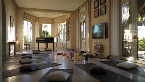 Meditation-and-yoga-studio-in-a-private-home-with-piano-and-bay-window-and-candles,-Wide-handheld-shot