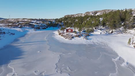 Traditionelle-Rote-Hütte-Am-Gefrorenen-Fluss-Im-Winter-In-Bessaker,-Trøndelag,-Norwegen