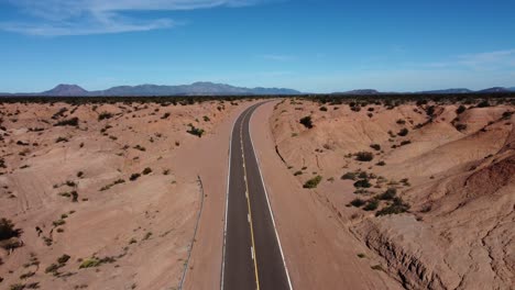 Luftaufnahmen-über-Der-Autobahnkurve-In-Einer-Riesigen-Red-Rock-Badland-Landschaft