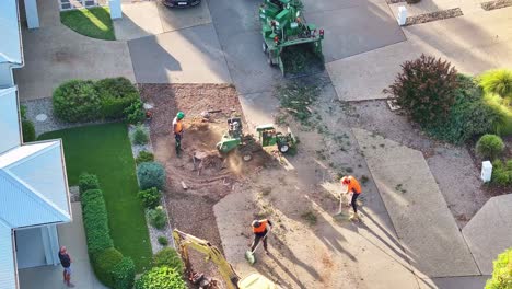 Yarrawonga,-Victoria,-Australia---6-March-2024:-Workers-raking-tree-rubbish-and-stump-grinder-working-the-stump-from-side-to-side-in-a-suburban-street