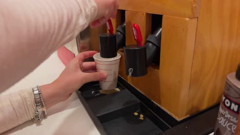 Woman-fills-a-cup-with-waffle-batter-to-make-Belgian-waffle-at-hotel-breakfast