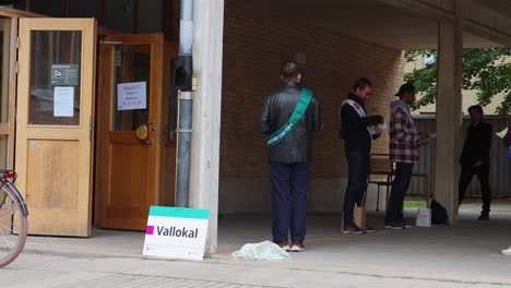 Workers-stand-by-polling-station-as-people-enter-to-vote-in-Stockholm