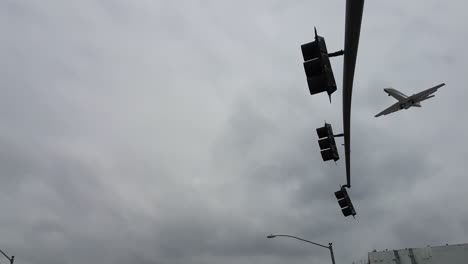 Airplane-Landing-on-San-Diego-Airport,-Flying-Above-Cars-and-Buildings-Under-Cloudy-Sky,-Tracking-Shot