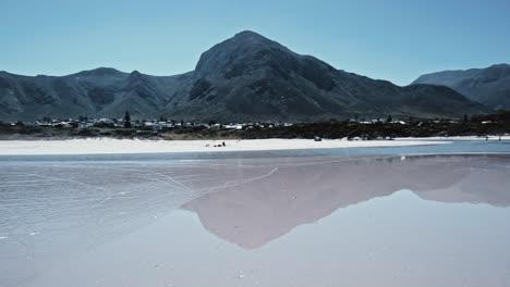 Mountains-reflect-on-wet-sand-on-a-beach-in-Hermanus-South-Africa