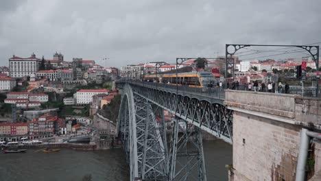 Scenic-Porto-Tram-Ride-over-Iconic-Ponte-Luís-I-Bridge,-Tourists-Enjoying-Historic-Cityscape-and-River-Views