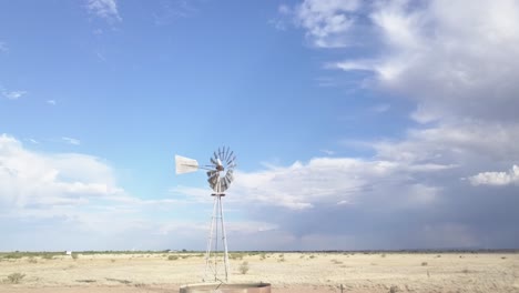 Drone-—-low-angle,-slowly-moving-across-the-landscape-with-windmill-and-skies-in-background,-Texas