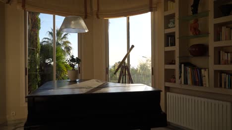 Brass-telescope-and-Piano-with-bay-window-and-small-bookshelf-with-sun-shining,-Handheld-shot